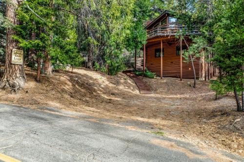 a log cabin in the woods next to a road at Tahquitz Rock Lodge in Idyllwild
