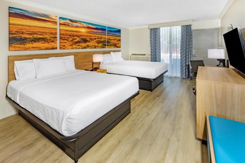 a hotel room with two beds and a flat screen tv at Days Inn by Wyndham Del Rio in Del Rio