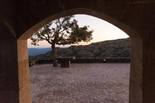 an archway with a tree and a bench on a mountain at Casal dos Netos in Penhas da Saúde