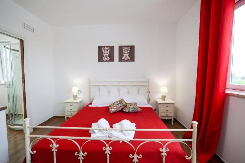 a bedroom with a red bed with red curtains at Cà del Re Holiday in Partinico