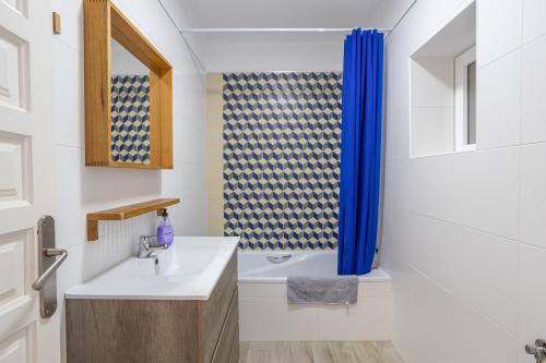 a bathroom with a sink and a blue shower curtain at Casa La Intemporal in Nerja