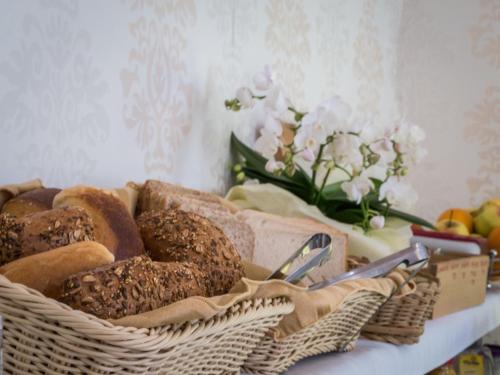 a basket of bread on a table with a vase of flowers at Hotel Luisenhof in Wiesbaden