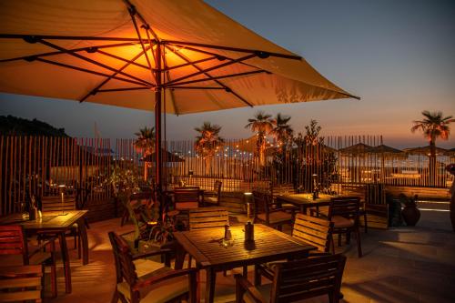 a restaurant with tables and umbrellas on a patio at Maya Beach Resort in Massa Lubrense