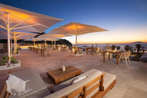 a patio with tables and umbrellas with a view of the ocean at Maya Beach Resort in Massa Lubrense