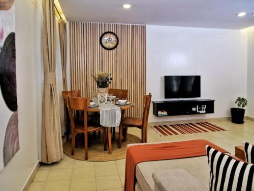 a living room with a table and a clock on a wall at Zendo Suite in Nairobi