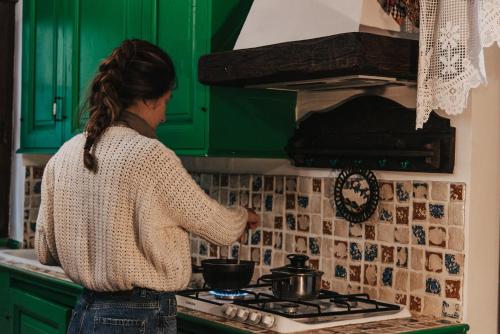 a woman standing in a kitchen with a pot on a stove at Monte Pratello - Dimora Rosy in Roccaraso