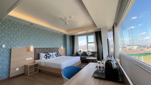 um quarto de hotel com uma cama e uma grande janela em Aurora Boutique Hotel Imphal em Imphal