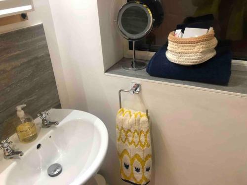 a bathroom with a sink and a mirror and a towel at The Studio on The Green in Egham