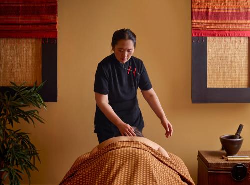 a woman is ironing a blanket on a bed at Careys Manor Hotel & SenSpa in Brockenhurst