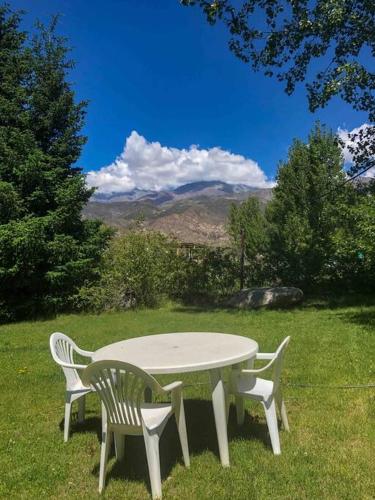 a white table and two chairs in the grass at Casa de montaña en un lugar mágico in Potrerillos