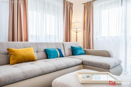 una sala de estar con un sofá gris con almohadas azules y amarillas en Apartament Ghimbav_RK, en Ghimbav