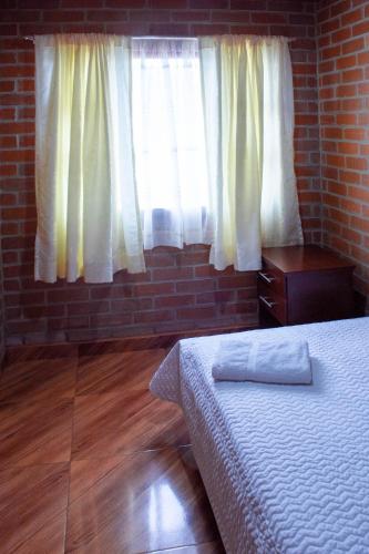 a bedroom with a bed and a brick wall at La Gran Estancia Hotel Campestre in Chachagüí