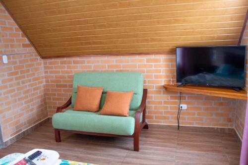 a green chair with two pillows sitting next to a tv at La Gran Estancia Hotel Campestre in Chachagüí