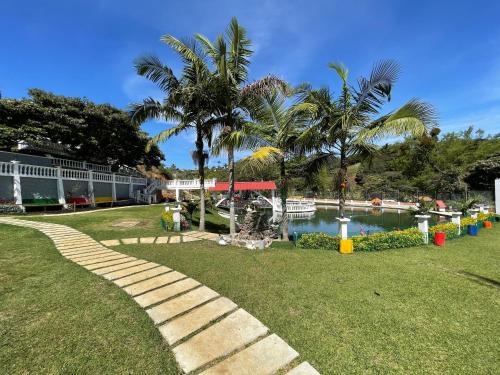 a park with a walkway and a pond with palm trees at La Gran Estancia Hotel Campestre in Chachagüí