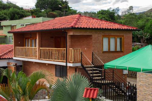 a small brick house with a balcony and a green umbrella at La Gran Estancia Hotel Campestre in Chachagüí