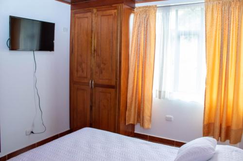 a bedroom with a bed and a television and a window at La Gran Estancia Hotel Campestre in Chachagüí