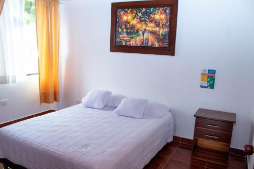 a bedroom with a white bed and a painting on the wall at La Gran Estancia Hotel Campestre in Chachagüí