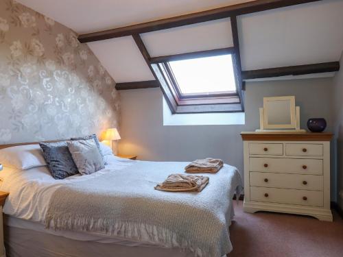 a bedroom with a bed and a window and a dresser at Oak Leaves Cottage in Newton Abbot