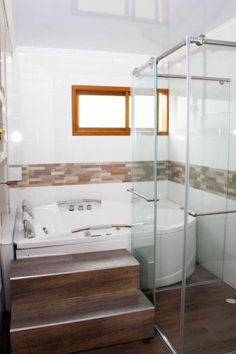 a bathroom with a glass shower and a tub at La Gran Estancia Hotel Campestre in Chachagüí