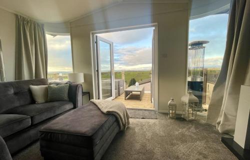 a living room with a couch and a large window at Ribble Valley Lodge Retreat in Gisburn