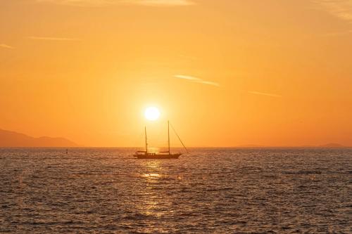 a sail boat in the ocean at sunset at Maya Beach Resort in Massa Lubrense