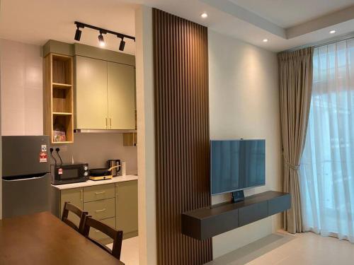a kitchen with a television and a counter with a table at MyHome @ Riverine Resort Kuching in Kuching