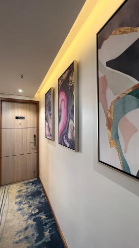 a hallway with paintings on the wall and a door at Aurora Boutique Hotel Imphal in Imphal