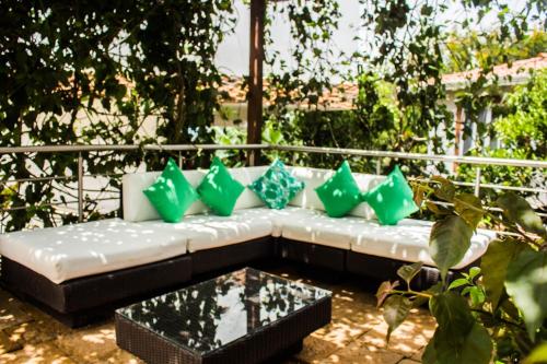 a white couch with green pillows on a patio at Hotel Mansión Barichara in Barichara