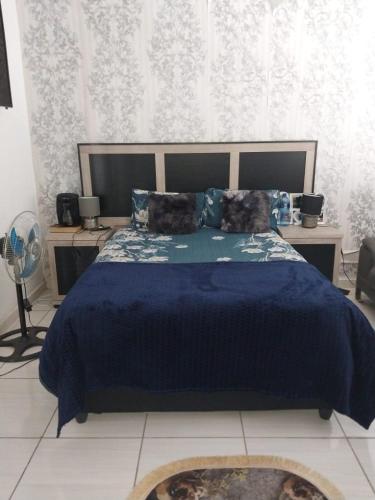 a bedroom with a bed with a blue comforter at Vaal holiday home in Vanderbijlpark