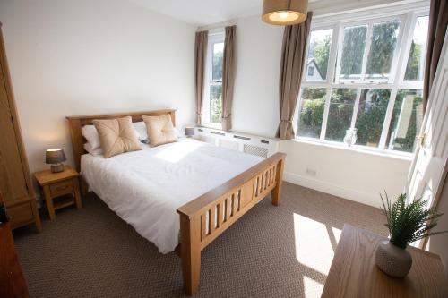 a bedroom with a large bed with white sheets and windows at 1 Bodwen Villas in Llangollen