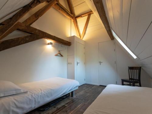 un dormitorio en el ático con 2 camas y una silla en De Jager en de gelagkamers, en Gouwelaar