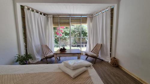 a bedroom with a table and chairs and a window at Departamento de huéspedes con piscina y parrilla, Tranquilo y Céntrico in Colonia del Sacramento