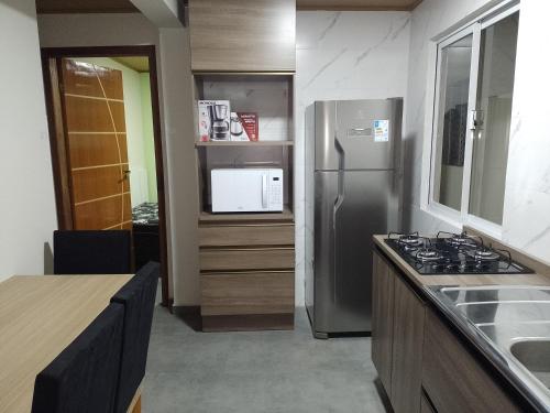 a kitchen with a stainless steel refrigerator and a microwave at Pousada Oliveira in Florianópolis