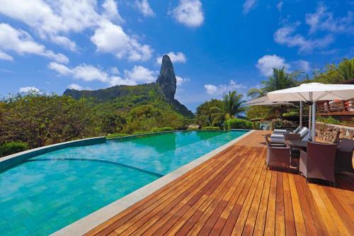 a pool at a resort with a mountain in the background at Pousada Zé Maria in Fernando de Noronha