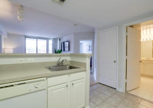 a kitchen with white cabinets and a sink and a door at Fantastic 1BD Condo At Ballston With Gym in Arlington