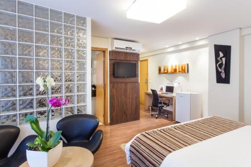 Habitación de hotel con cama, mesa y sillas en Ramada Hotel & Suites Lagoa Santa By Wyndham en Lagoa Santa