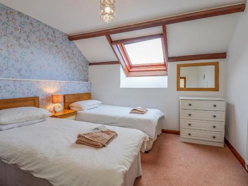 a bedroom with two beds and a window at Acorn Cottage in Newton Abbot