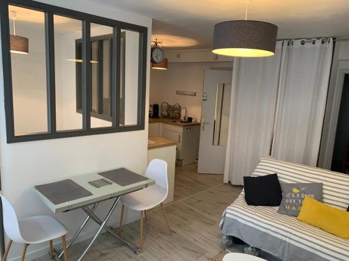 a living room with a table and a couch at L'Oasis Marin meublé, lumineux et cosy à 1min à pied du marché dans l'hyper centre de La Rochelle avec TV et Wifi in La Rochelle