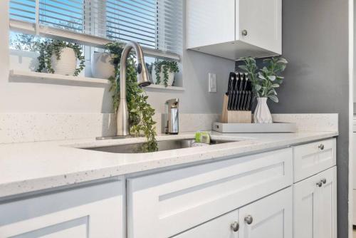 Una cocina con gabinetes blancos y un fregadero. en Roxanas 3bed 2bath Home with Modern Interior and BBQ Backyard, en Fort Lauderdale