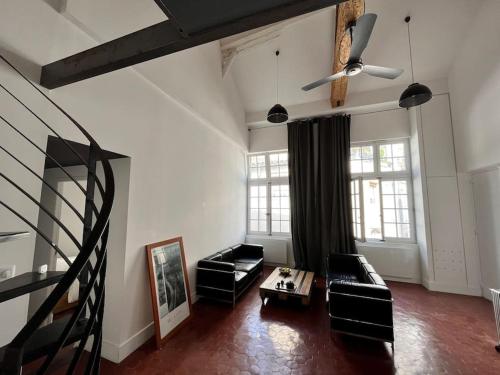 a living room with black furniture and a ceiling fan at Atelier 84 - AC - Loft - Avignon Centre Ville in Avignon