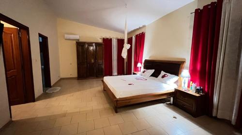 a bedroom with a bed and red curtains at Diouf house in Somone