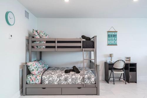 a bedroom with two bunk beds and a desk at The Purple Pelican Beachfront with Ocean Balcony Unit 4 in Fort Lauderdale