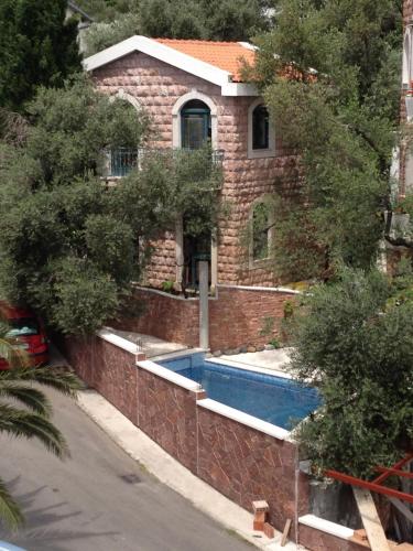 a brick house with a swimming pool in front of it at Apartments and Rooms Levantin Inn in Sveti Stefan