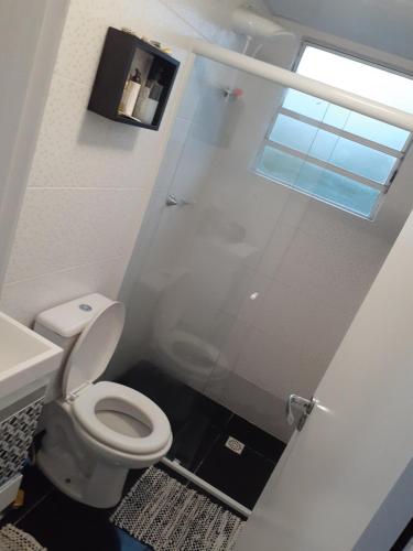 baño con aseo y puerta de ducha de cristal en Apto Rústico comfy Garg wifi próx a políc Federal serve 5 hóspedes, en Curitiba