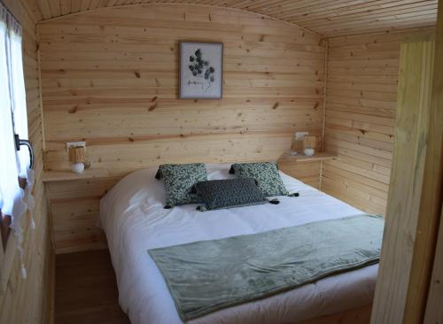 a bedroom with a bed in a wooden cabin at Les Roulottes des Ris in Vallon-en-Sully