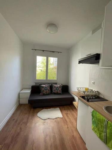 un salon avec un canapé noir dans une cuisine dans l'établissement Studio paisible Paris 20, à Paris