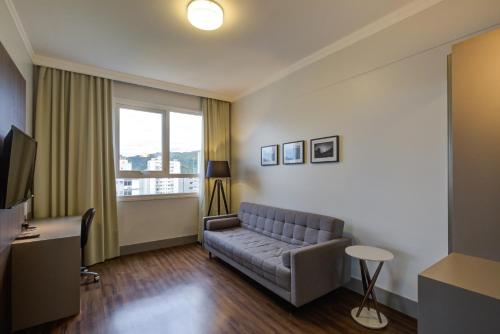 a living room with a couch and a window at Slaviero Blumenau in Blumenau