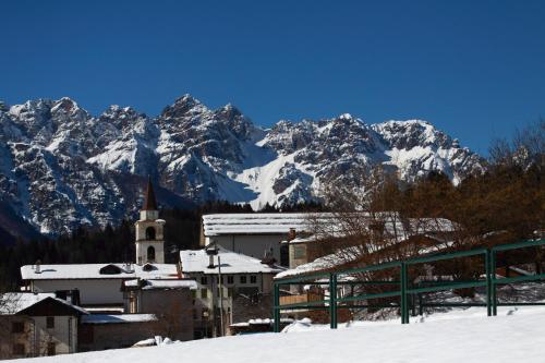 a snow covered mountain range with a church and a town at Albergo Diffuso Dolomiti in Forni di Sotto