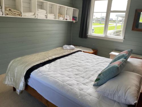 Schlafzimmer mit einem Bett und einem Fenster in der Unterkunft Barbwire Bach in Opunake