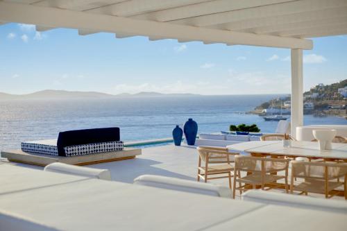 a patio with a table and chairs and the ocean at Mykonos Grand Hotel & Resort in Agios Ioannis Mykonos